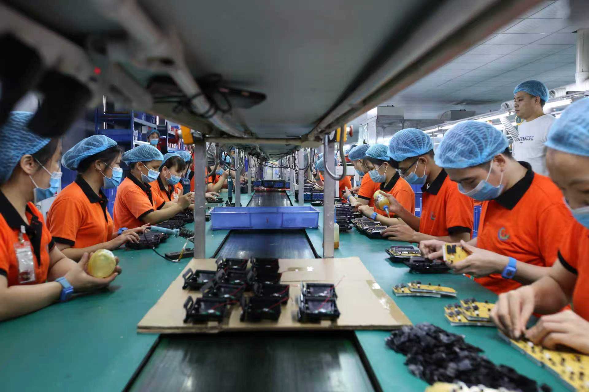 Operators assembling electronics on a controlled production line