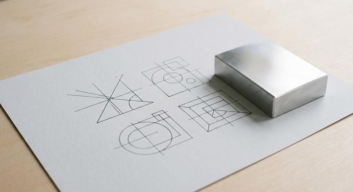 Geometric technical sketch and precise metallic block demonstrating clean factory tooling design