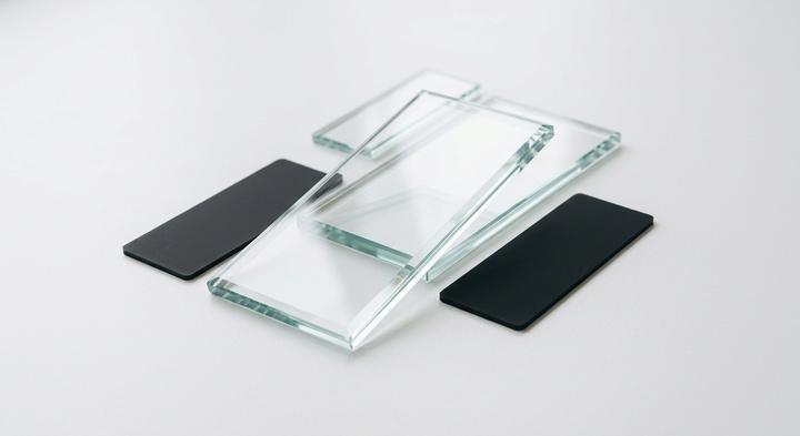 Blank, elegant glass display substrates resting on a clean white surface with soft studio reflections