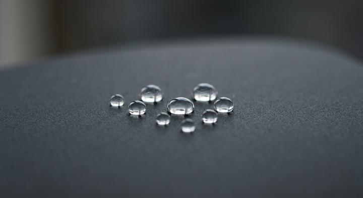 Macro view of water droplets on a highly hydrophobic matte surface showing liquid resistance